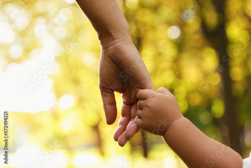 Fototapeta Daughter holding mother's hand outdoors, closeup. Happy family
