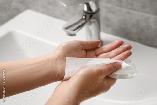 Woman wiping hands with paper towel in bathroom  closeup