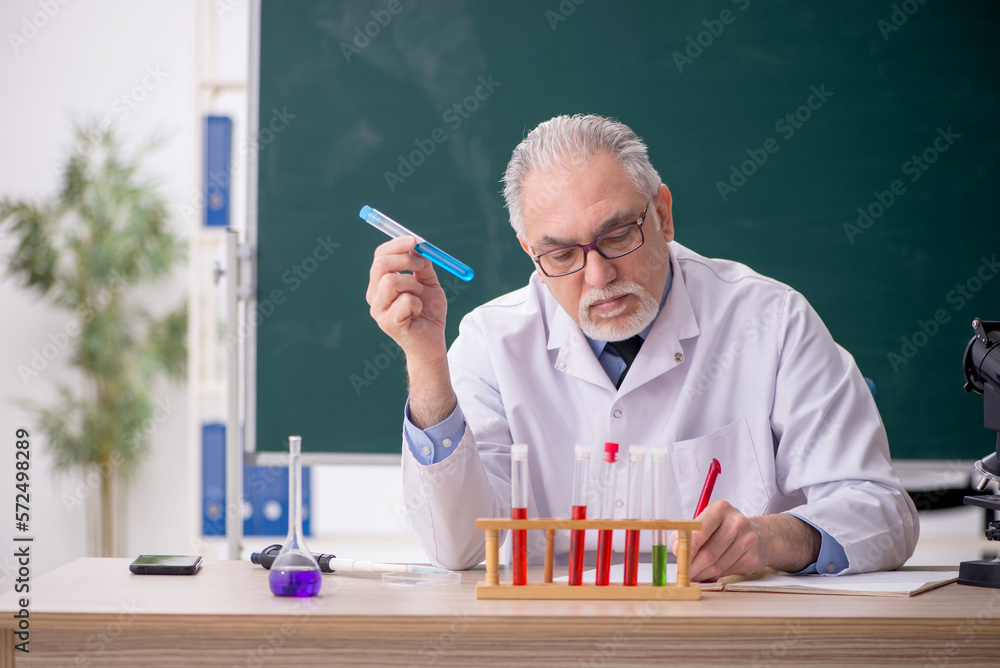 Old male chemist teacher sitting in the classroom Old male chemist teacher sitting in the classroom