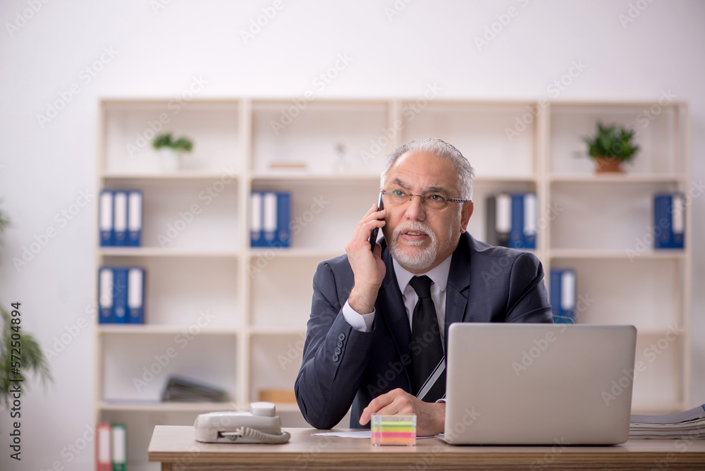 Old male employee working in the office Old male employee working in the office