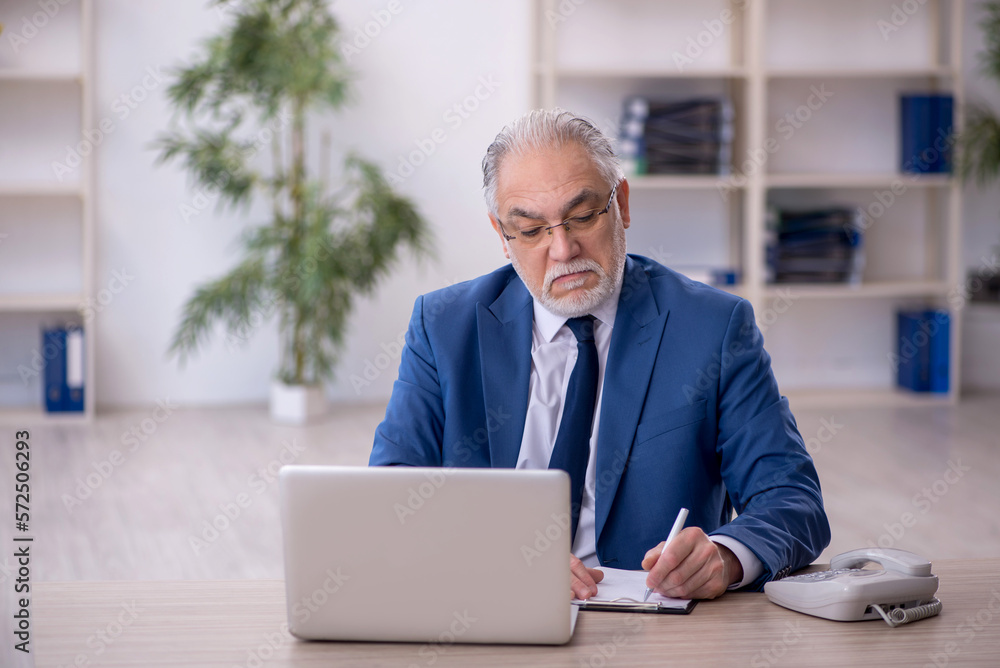 Old male boss working at workplace Old male boss working at workplace