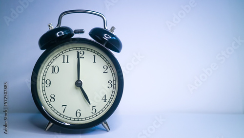 Background photo of an alarm clock showing 5:00 