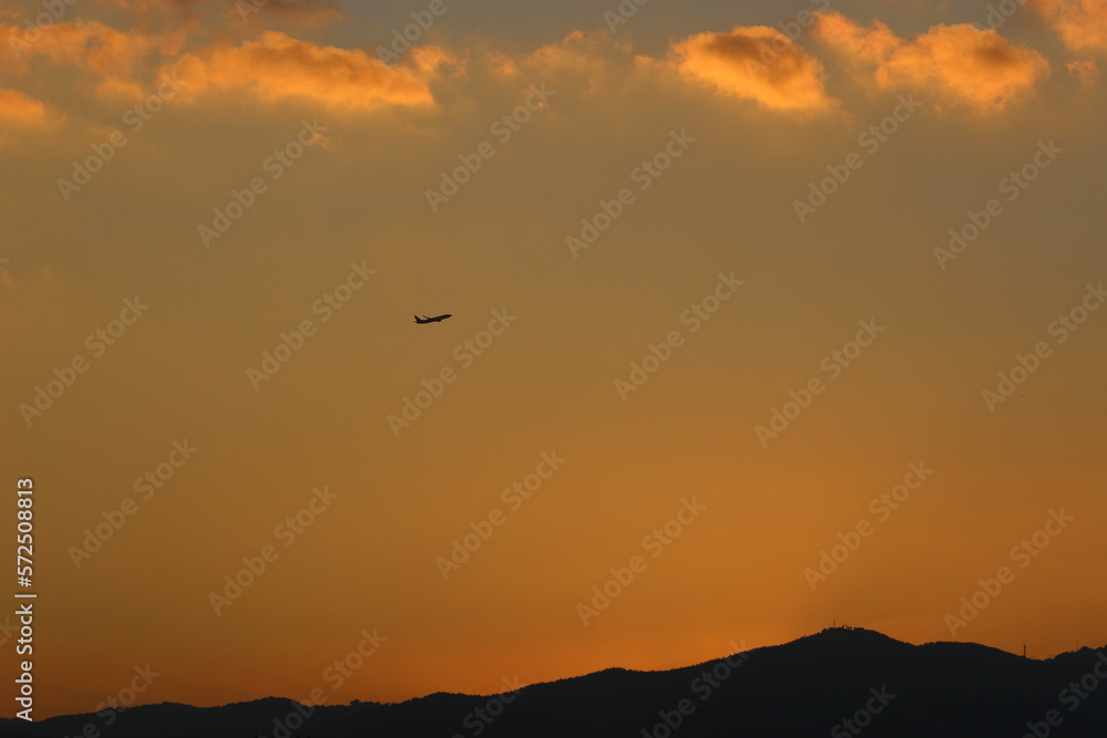 red sunset sky in the clouds, golden hour abstract clouds, plane in distance