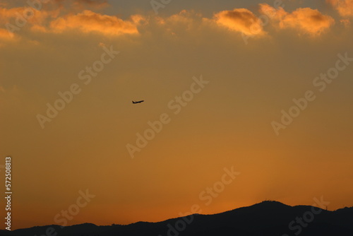 red sunset sky in the clouds, golden hour abstract clouds, plane in distance © Anna Elizabeth