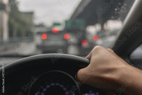 Man hand hold car wheel, driving car on traffic jam road in asia. © Sevendeman