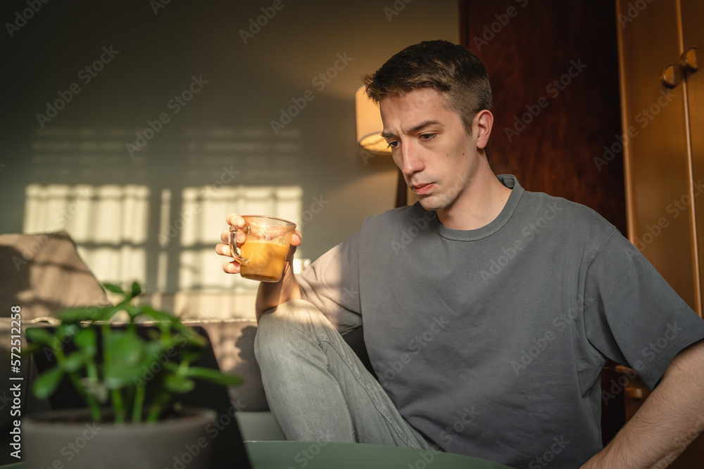 A young guy is using his laptop to study or do business from home A young guy is using his laptop to study or do business from home