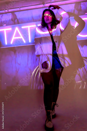 silhouette of a young beautiful woman on the background of neon projector inscriptions, slight blur