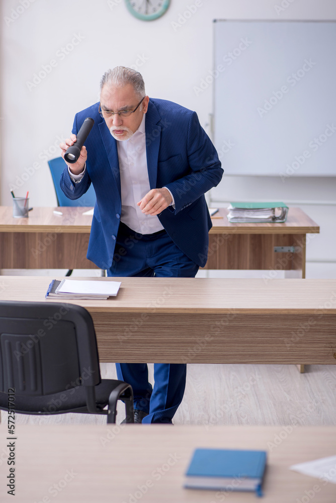 Old male teacher holding penlight in the classroom Old male teacher holding penlight in the classroom