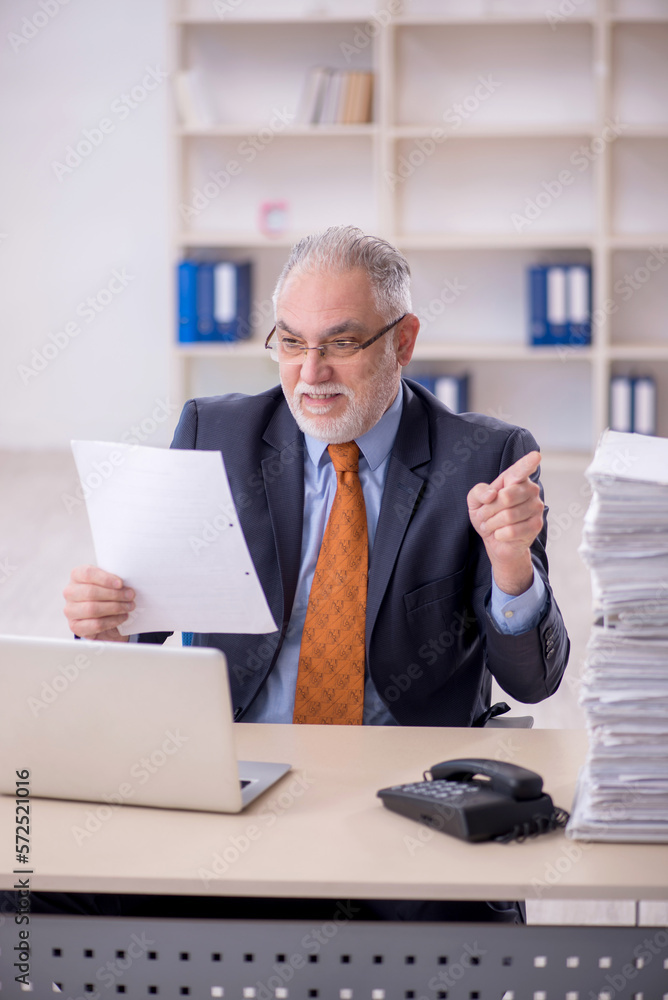Old male employee unhappy with excessive work in the office Old male employee unhappy with excessive work in the office