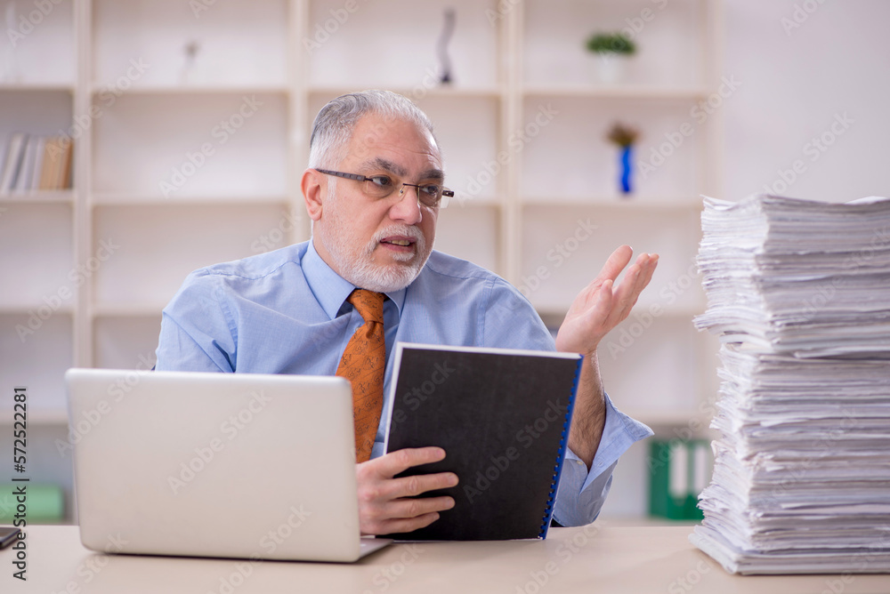 Old male employee unhappy with excessive work in the office Old male employee unhappy with excessive work in the office