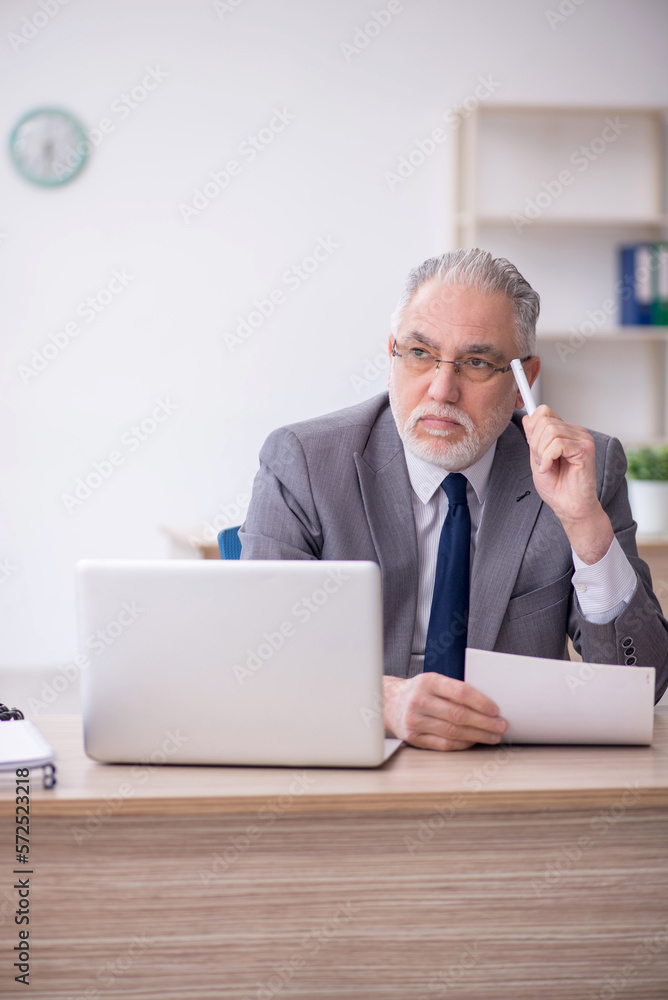 Old male employee working in the office Old male employee working in the office