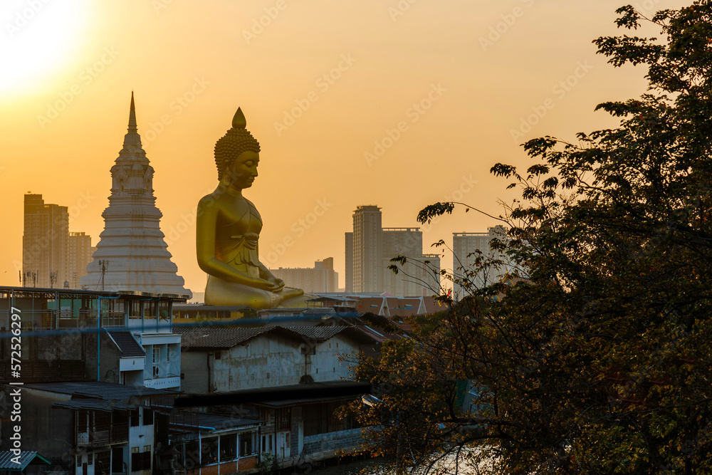 Big Buddha statue at Wat Paknam Phazi Charoen with the city and beautiful sunset in the background