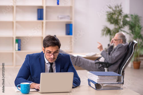 Old male boss and young male employee in the office