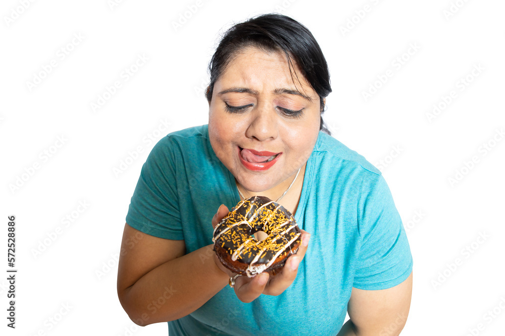 Overweight fat indian woman tempting to eat delicious chocolate donut isolated over white background,studio portrait. Overweight fat indian woman tempting to eat delicious chocolate donut isolated over white background,studio portrait.