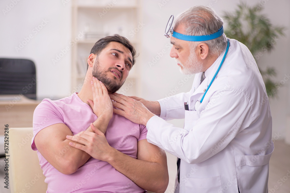 Young male patient visiting old male doctor otologist Young male patient visiting old male doctor otologist