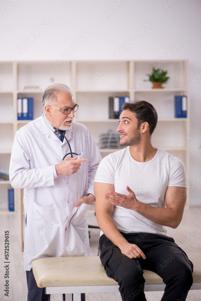 Fototapeta premium Young male patient visiting old male doctor