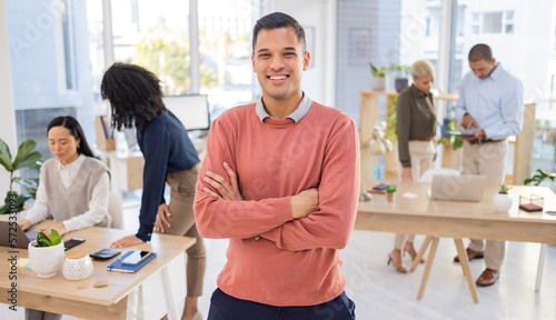 Portrait, startup and businessman or intern happy at new job or company in a modern office arms crossed with smile. Happy, confident and excited young male employee or worker at the workplace