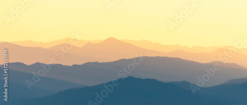 Panoramic scene of bright sunlight over the layers of mountain range.