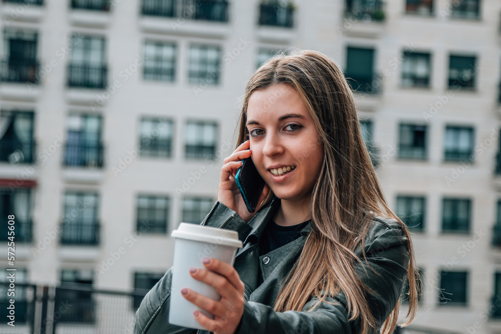 Fototapeta premium urban woman talking with mobile phone and coffee to go
