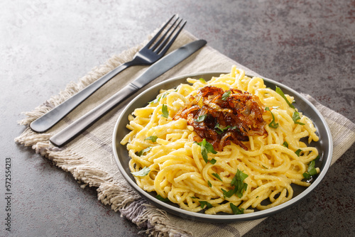 Spatzle egg noodles with melted cheese and fried onions on top close-up in a plate on the table. Horizontal
