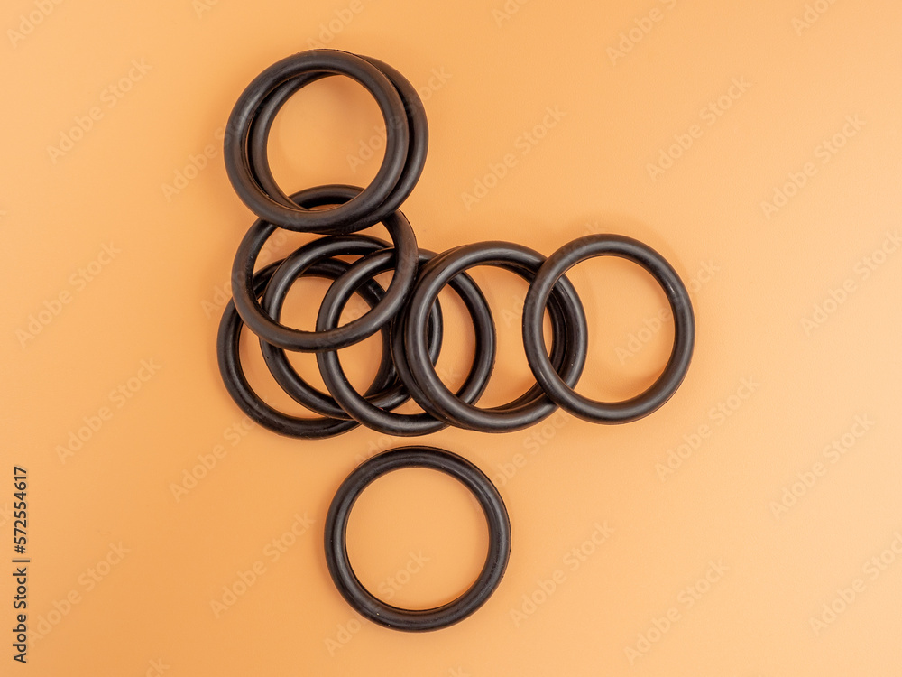 Hydraulic and pneumatic o-rings in black in different sizes on an orange background. Rubber gaskets for plumbing. copy space. Hydraulic and pneumatic o-rings in black in different sizes on an orange background. Rubber gaskets for plumbing. copy space.