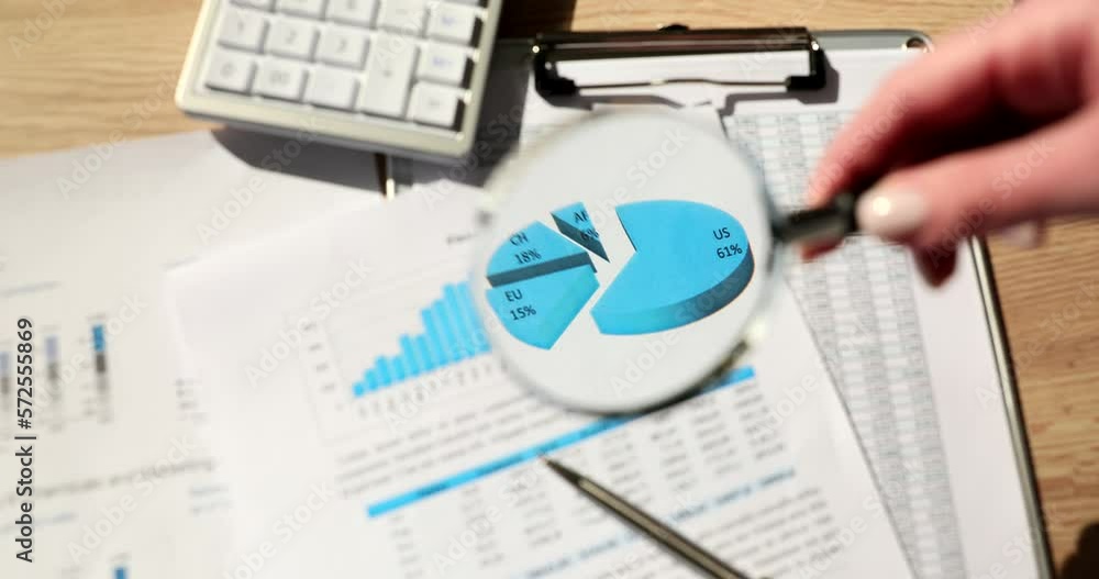 Analyst holding magnifying glass on graphic analytic chart on paper Analyst holding magnifying glass on graphic analytic chart on paper