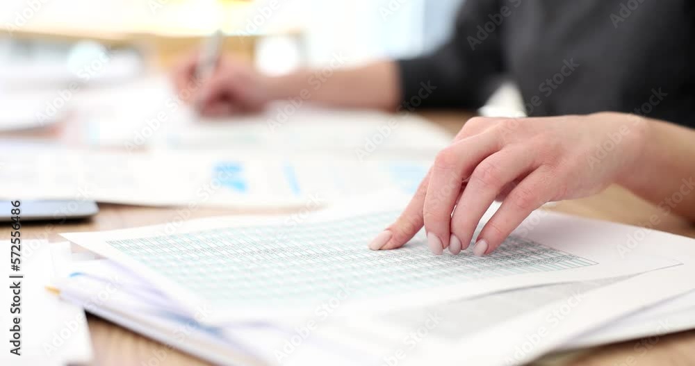 Hand of business woman points finger at the financial report in numbers checking balance Hand of business woman points finger at the financial report in numbers checking balance