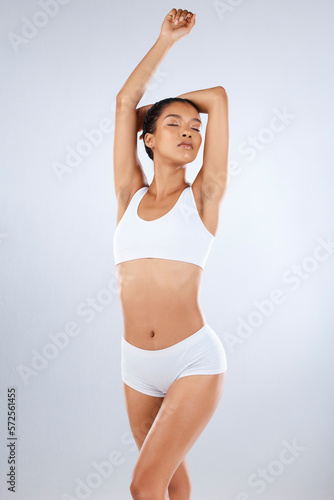 Health, wellness and body care, woman in underwear with healthy diet, exercise and balance in studio. Fitness, nutrition and healthcare, motivation for slim and fit figure isolated on grey background © Clayton D/peopleimages.com