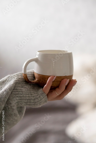 Clay cup with coffee in hand on white background