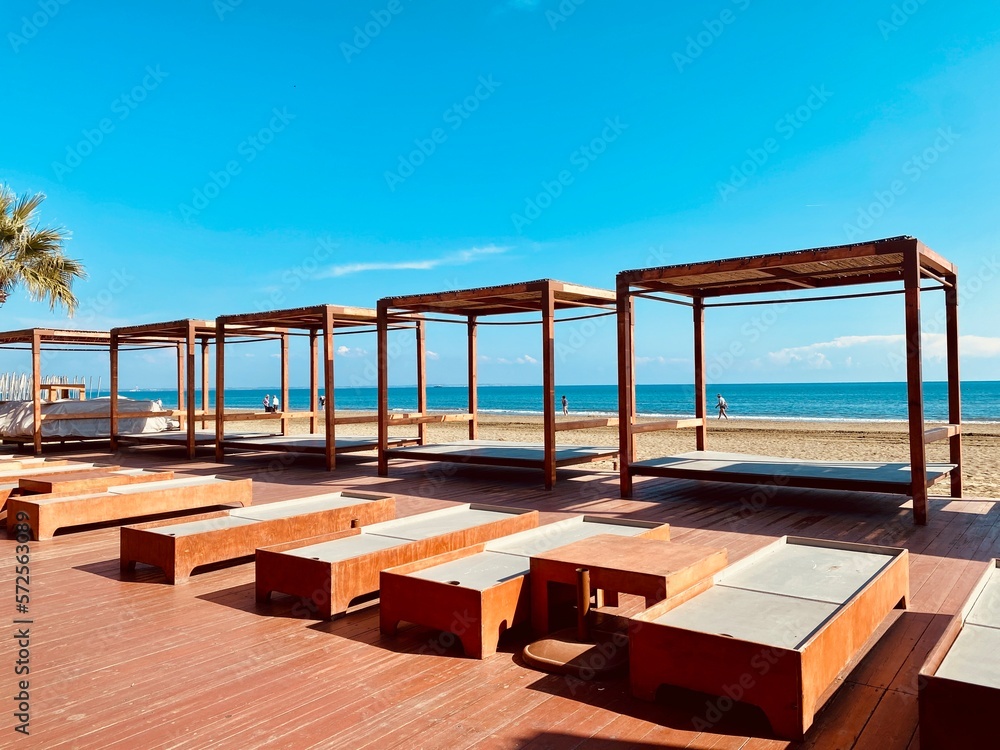 Fototapeta premium Sunbeds loungers at ocean resort, sea view in distance