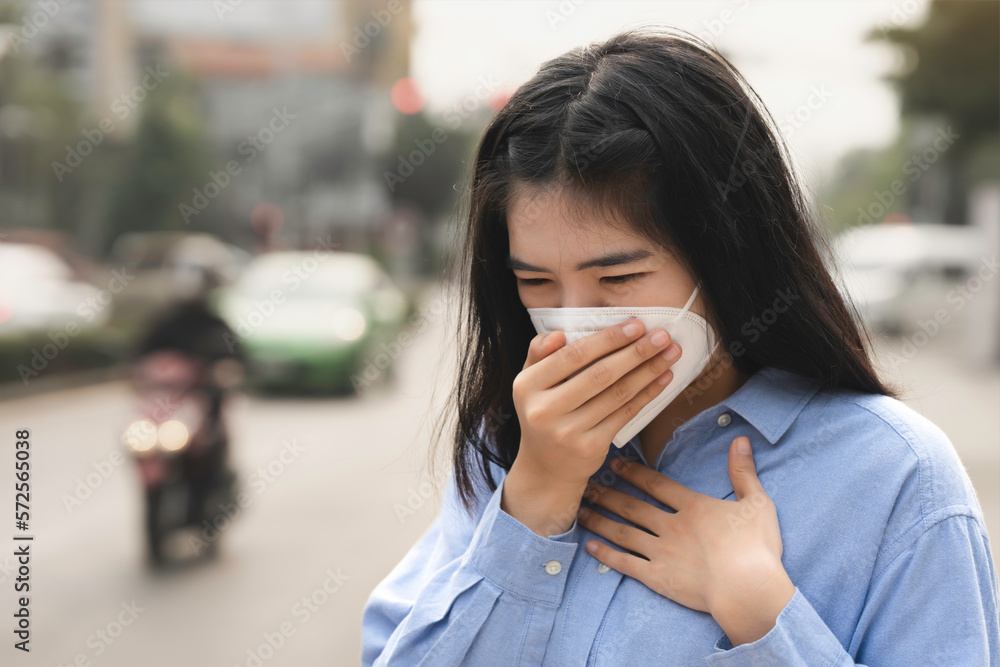 Asian woman wearing the N95 Respiratory Protection Mask against PM2.5 air pollution and headache Suffocate. City air pollution concept Asian woman wearing the N95 Respiratory Protection Mask against PM2.5 air pollution and headache Suffocate. City air pollution concept