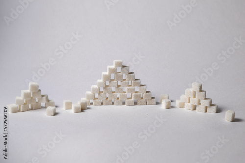 Sugar cubes in pyramid shape on white background, conceptual image.