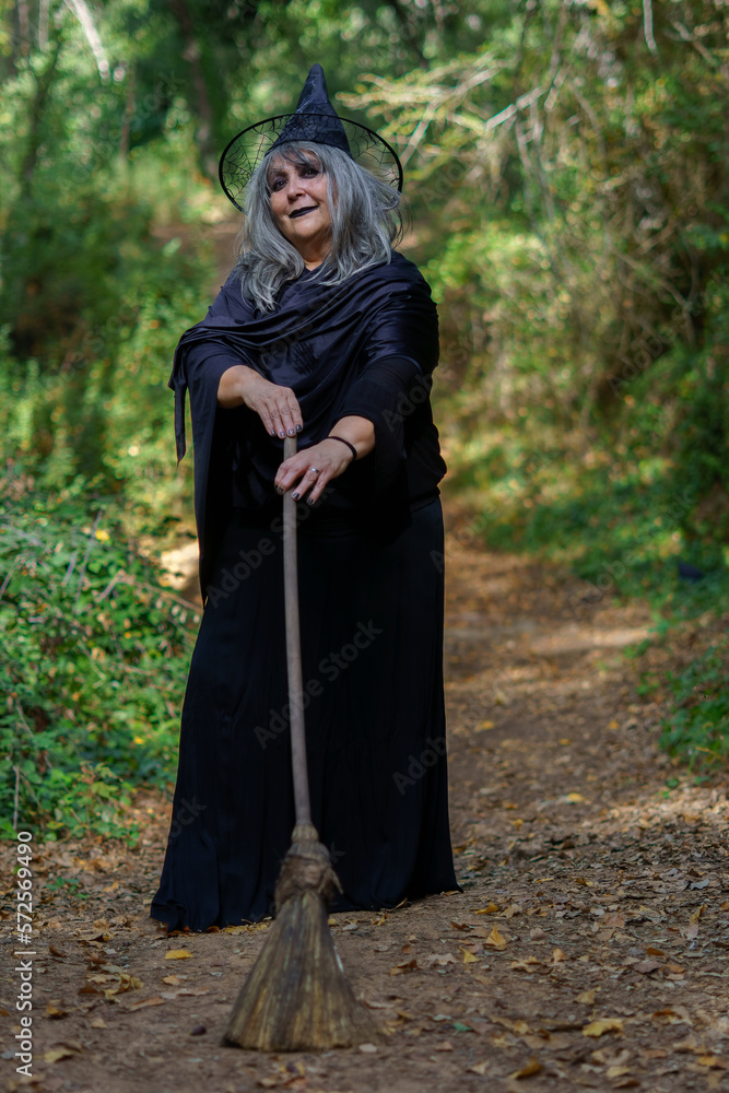 white-haired witch with her broom on a forest trail white-haired witch with her broom on a forest trail