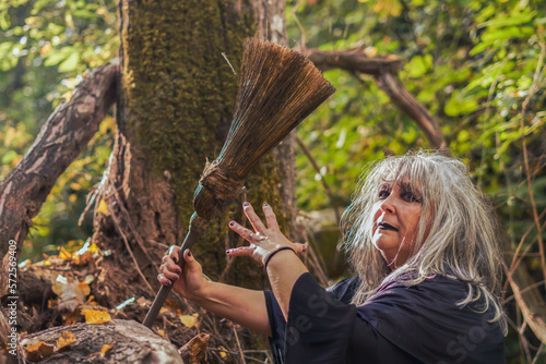 Foto witch with tousled white hair and broom in the forest