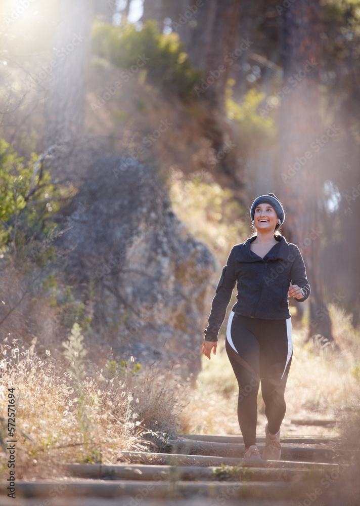 Fototapeta premium Earphones, music and woman hiking in nature outdoors for health, exercise and fitness. Winter walking, thinking and happy female hiker streaming radio, podcast or audio while trekking in forest park.