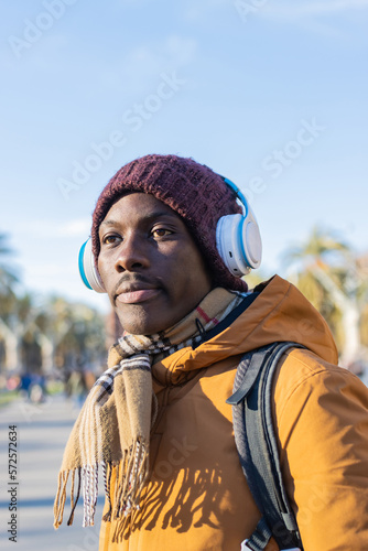 African man with headphones and winter clothes in the city.