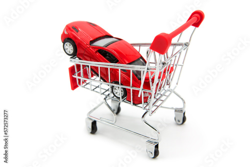 Car shopping. Red luxury sports car in supermarket shopping cart isolated on white background. 