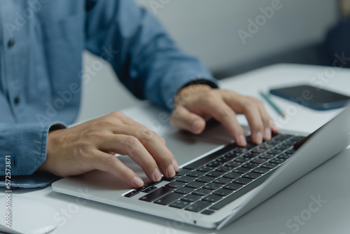 Man typing on keyboard laptop computer  searching for information or doing freelance work.Digital technology online network and social media concept.