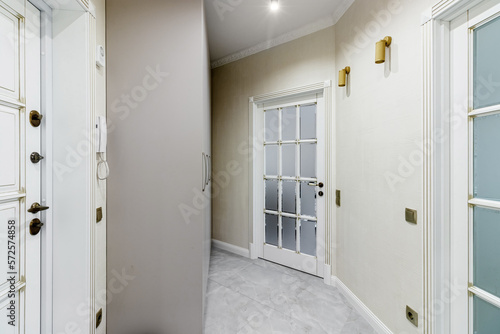 The interior of a stylish house in light colors with white doors with glass.