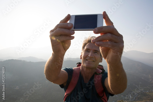 POV of mature man taking selfie with phone in mountains photo