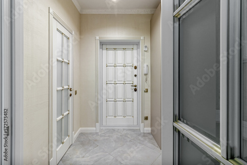 The interior of a stylish house in light colors with white doors with glass.