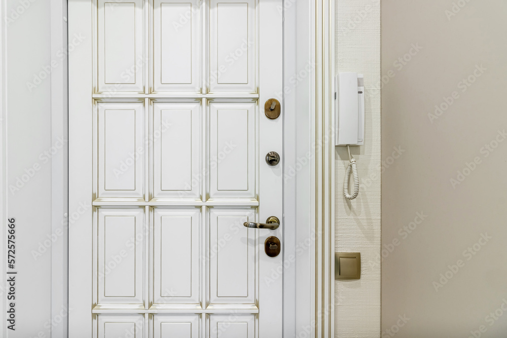 Close up of stylish and elegant door knob or handle on white door. Vintage white and bronze door handle on door that is suitable for refined home interior. Details concept
