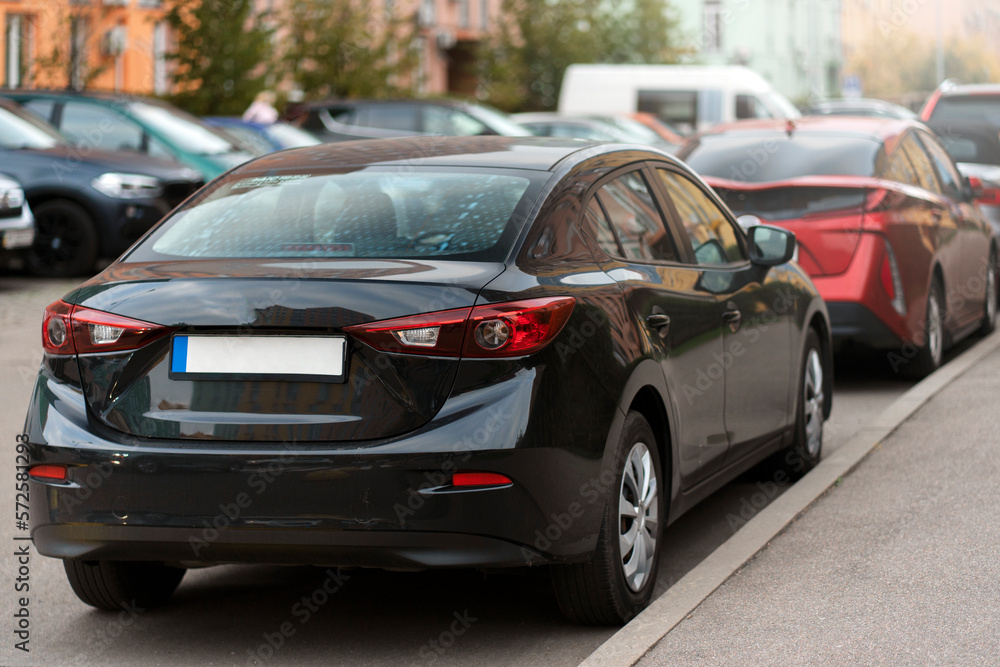 Black, new car is parked in one line. Car in the city, on the street.