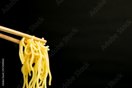 Quadro su tela egg noodle hold on a chopstick on a black background