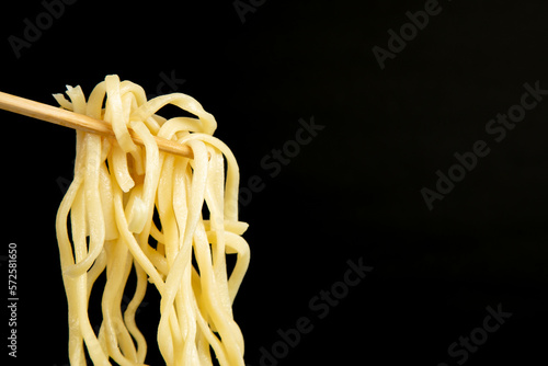 egg noodle hold on a chopstick on a black background