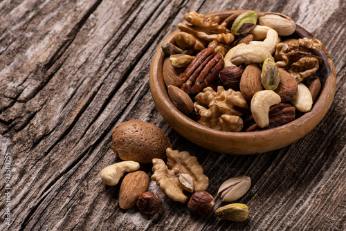variety of dried fruits in the bowl and on the old wooden table in extreme close-up.