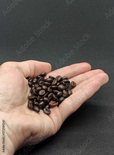 Coffee beans in man hand on a black background