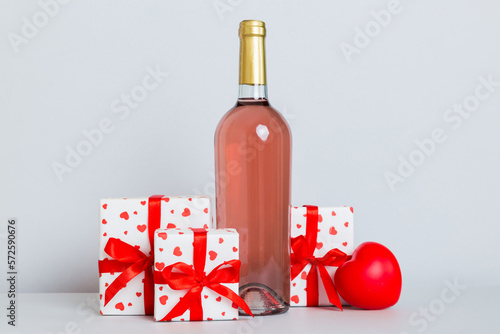 Bottle of wine on colored background for Valentine Day with gift box. Heart shaped with presrnt box perspective view with copy space photo