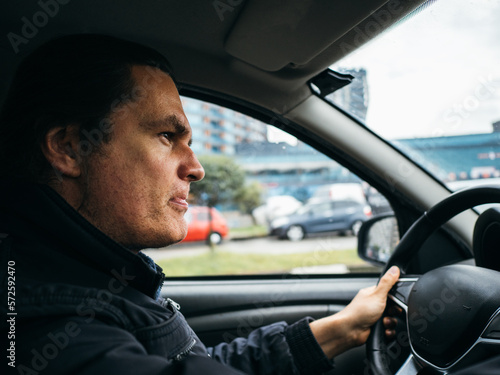 Portrait of stressed male driver driving car with serious expression. © DedMityay