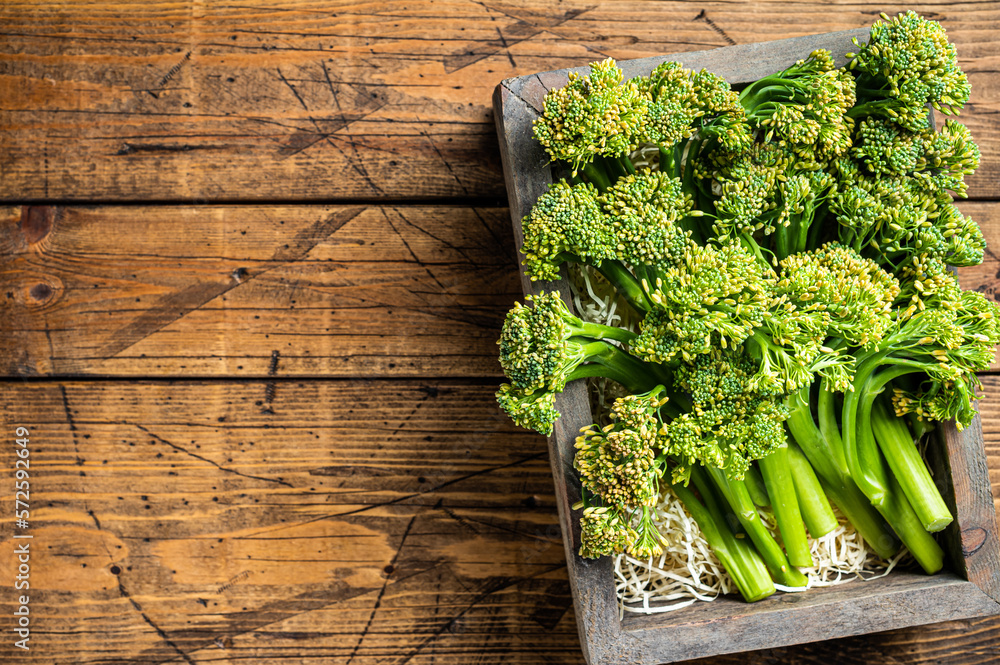 Raw Organic Fresh Broccolini Vegetable in a wooden box. Wooden background. Top view. Copy space